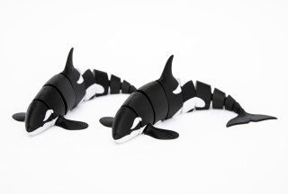 Two Orca plastic toys are displayed side by side on a white background.