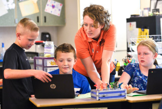 An instructor works with kids in a classroom.