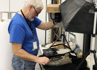 A volunteer assists in digitizing using a camera and lightbox to illuminate specimens