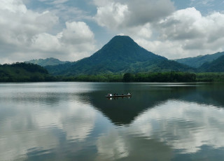 A canoe of people on a lake with a volcano in the background. 