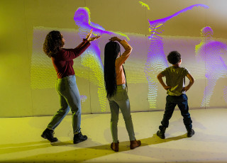 Three children play in front of an interactive screen.