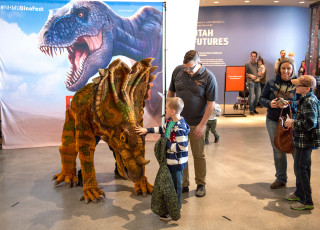 This is an image of a family playing with a model dinosaur.