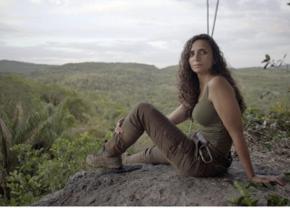 Ella Al-Shamahi sit on a rock ledge in the jungle.