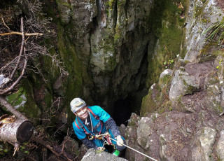 A scientist rappels into a cave. 