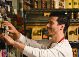 A man in a white shirt reaches for grocery products on a shelf
