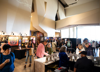 People walk around art booths in a large room