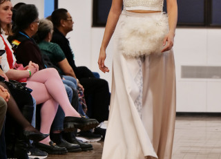 A young woman models a white garment with a fur accessory
