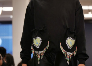 A young woman models a black garment with bead work