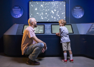 A man and child stand before a snowflake display