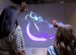 an adult and child look up at a digital mammoth display